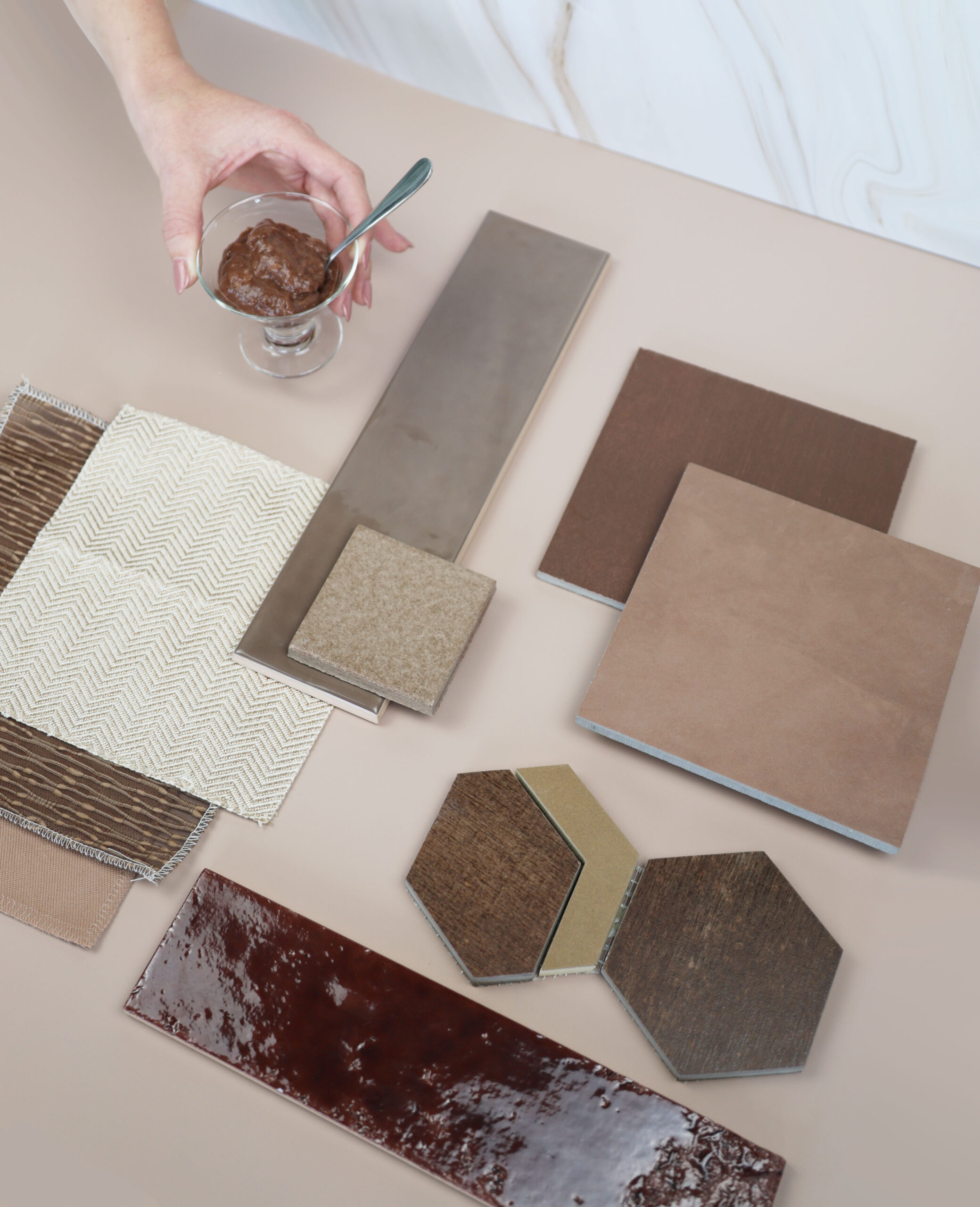 tiles laying on a tan background that are all similar brown tones. hand with Mocha Mouse cup